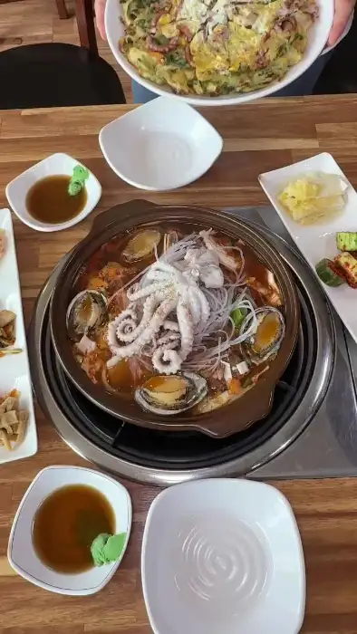 테이블에 놓인 다양한 음식들 - 소전복갈낙찜, 파전, 밥 등이 함께 보입니다.