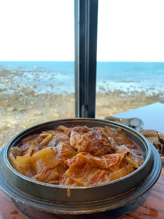 통창 너머로 보이는 푸른 바다와 함께 제공된 따뜻한 비주얼의 음식