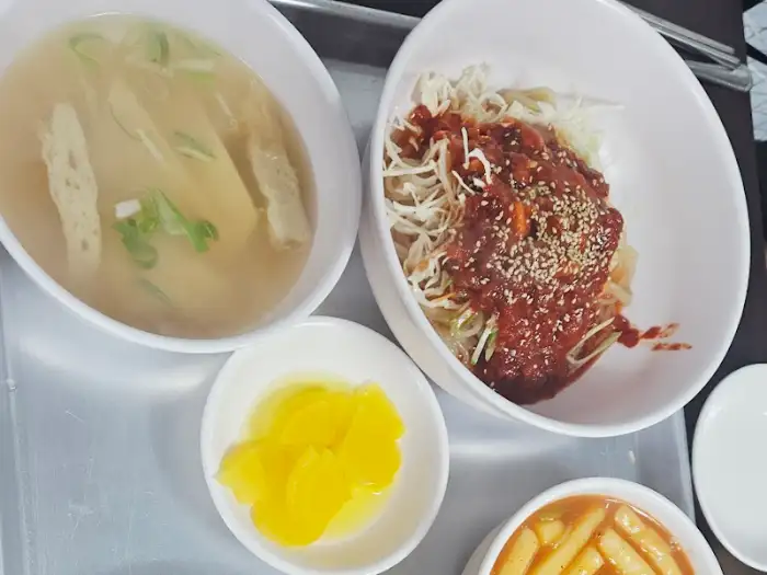 테이블 위에 놓인 쫄면, 오뎅국, 그리고 단무지