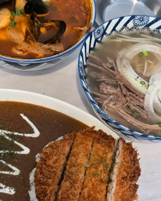 쌀국수와 돈까스 카레, 해산물 요리가 함께 담긴 상차림