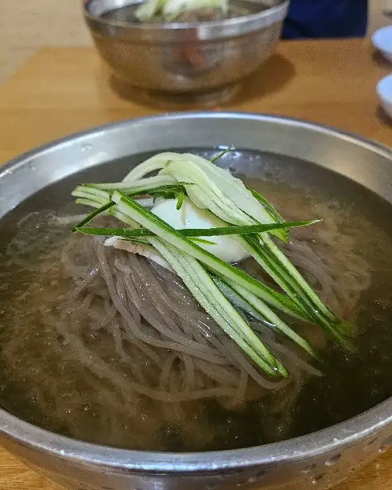 놋그릇에 담긴 물냉면. 얇게 썬 고기와 오이, 계란 지단이 고명으로 올라가 있습니다.