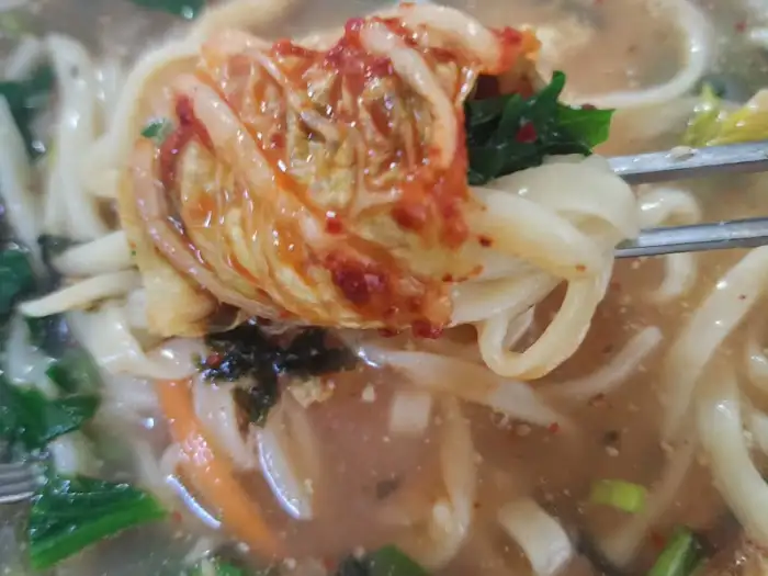 칼국수 면에 김치를 얹어 먹는 모습