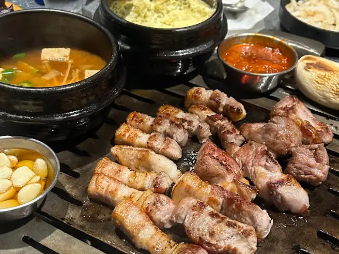 연탄불 위에서 구워지는 고기, 된장찌개, 계란찜, 쌈무