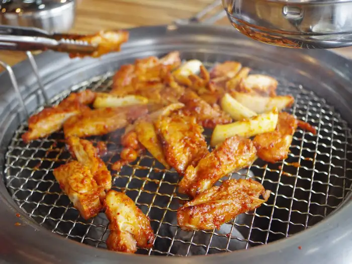 숯불 위에서 조리 중인 닭갈비와 떡