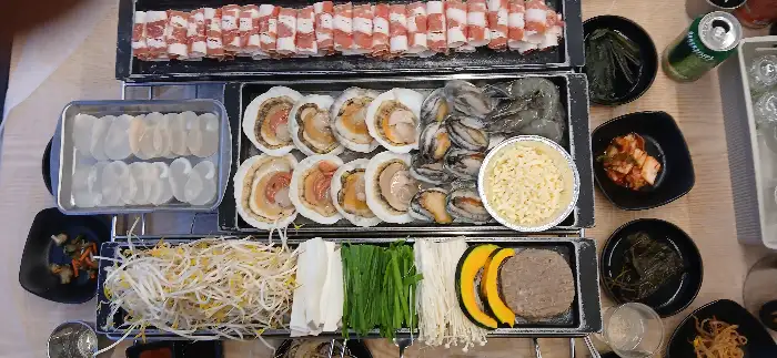 테이블에 놓인 다양한 삼합 재료와 곁들임 반찬