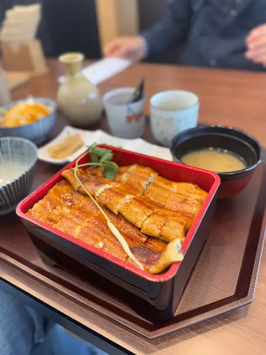 따뜻한 조명과 깔끔한 인테리어의 식당 내부 모습, 테이블 위에 놓인 정갈한 장어덮밥 세트