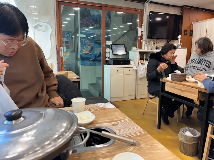 경원식당 내부 모습, 나무 테이블과 따뜻한 조명, 카운터석이 보인다.