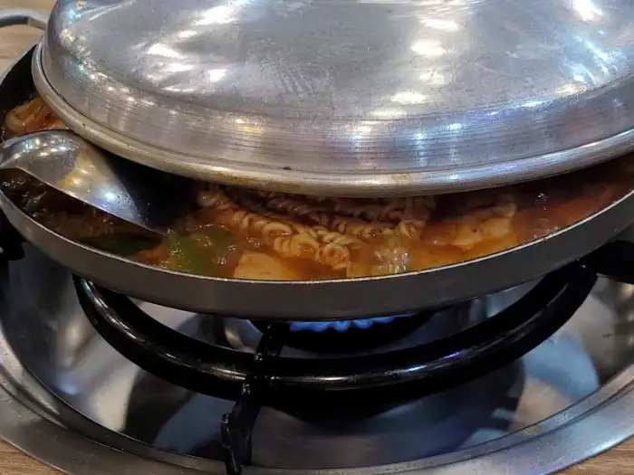 끓기 시작하는 부대찌개 냄비의 모습. 햄, 소시지, 라면 사리 등이 푸짐하게 보인다.