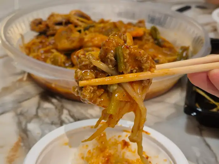 젓가락으로 집어 올린 아구찜 속 아구살과 채소