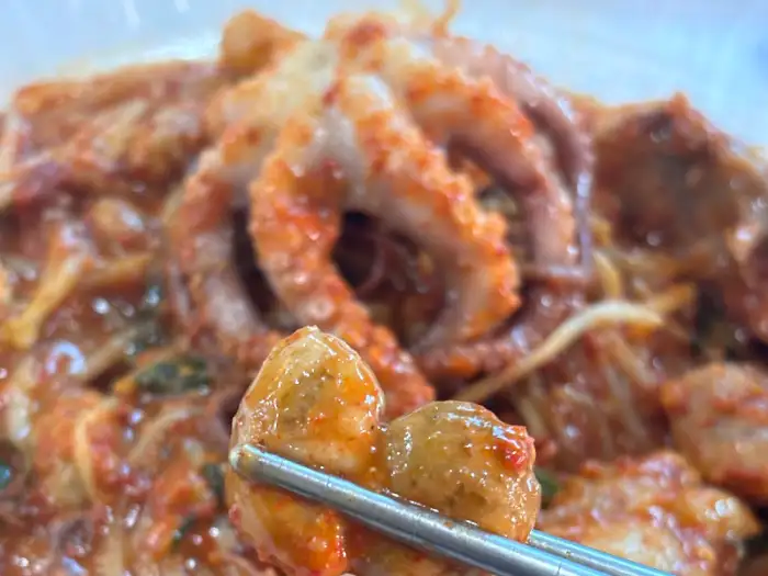 젓가락으로 집어 올린 아구찜 속 해산물
