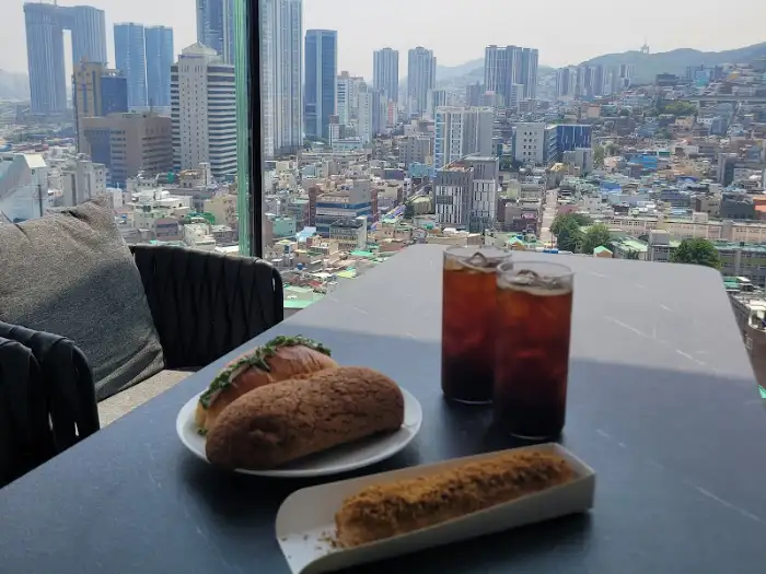 테이블 위에 놓인 커피와 빵, 그리고 배경의 도시 풍경