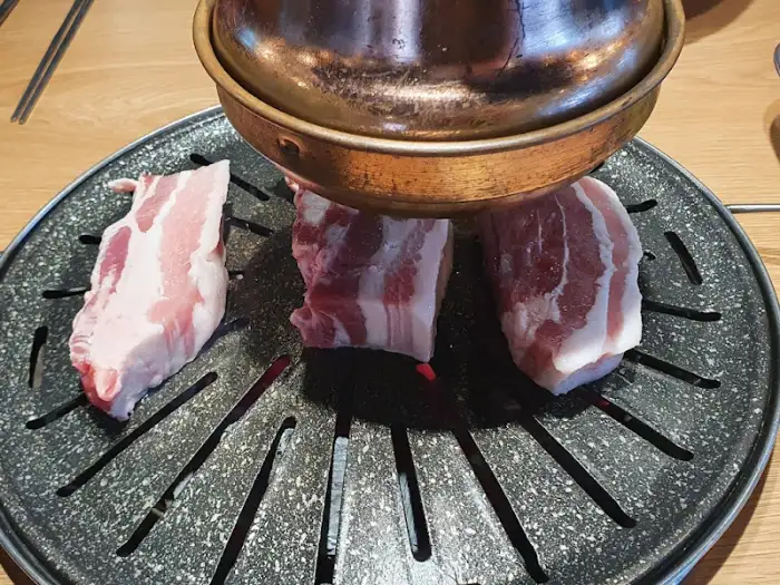 두툼한 삼겹살이 불판 위에서 구워지고 있는 모습