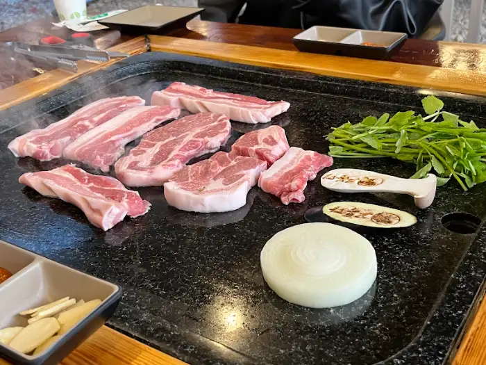 기름에 지글지글 익어가는 삼겹살과 쌈 채소, 양파