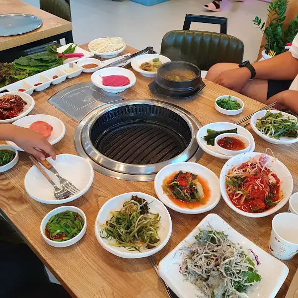 불판 위에서 익어가는 고기와 다양한 쌈 채소