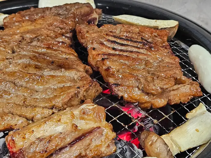 숯불 위에서 구워지는 두툼한 돼지갈비