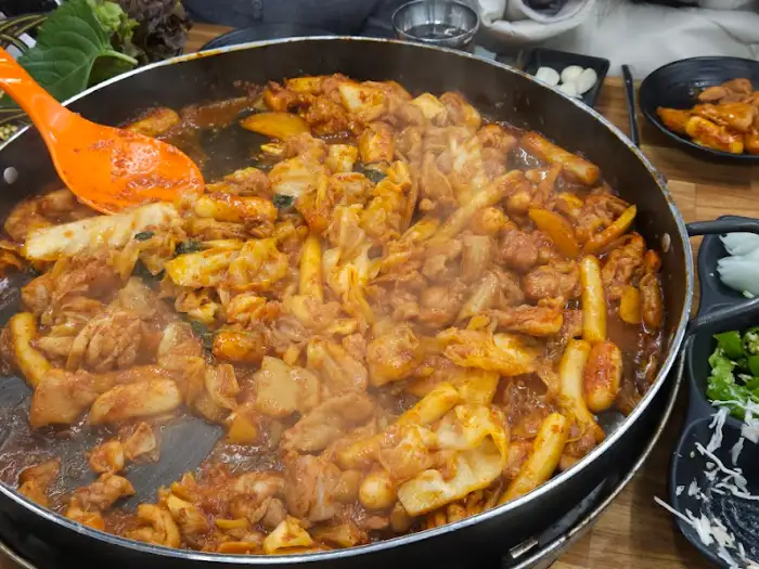 큼지막한 철판 위 닭갈비에 큼지막한 주걱으로 볶아내는 모습
