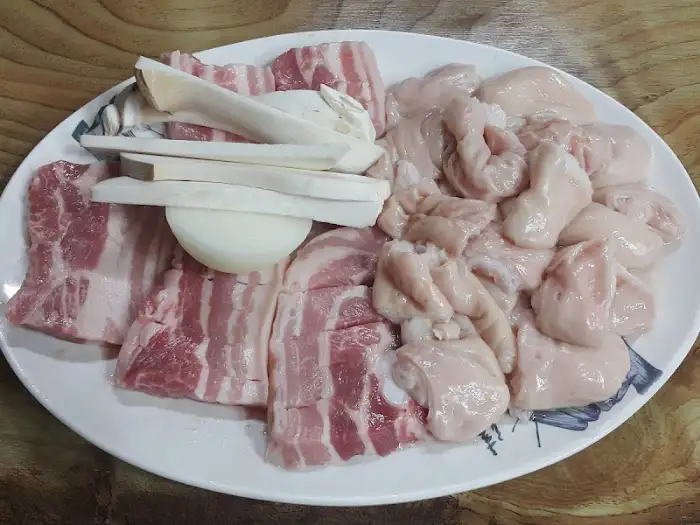 신선한 삼겹살, 버섯, 양파, 그리고 막창이 접시에 담겨 있다