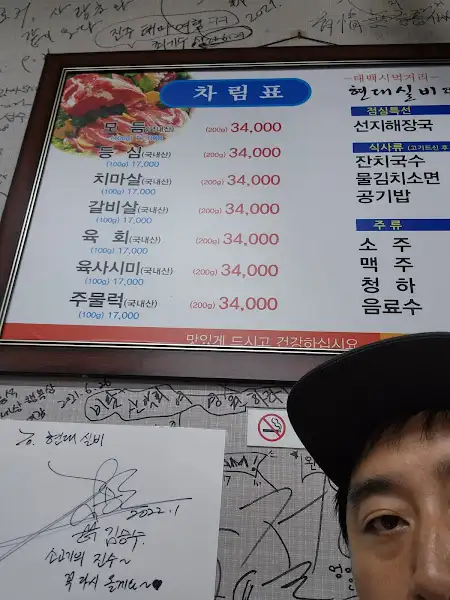 식당 내부 벽에 걸린 메뉴판 사진. 다양한 종류의 고기와 낙지 요리가 보인다.