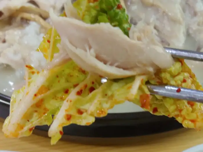 젓가락으로 집은 겉절이와 닭고기