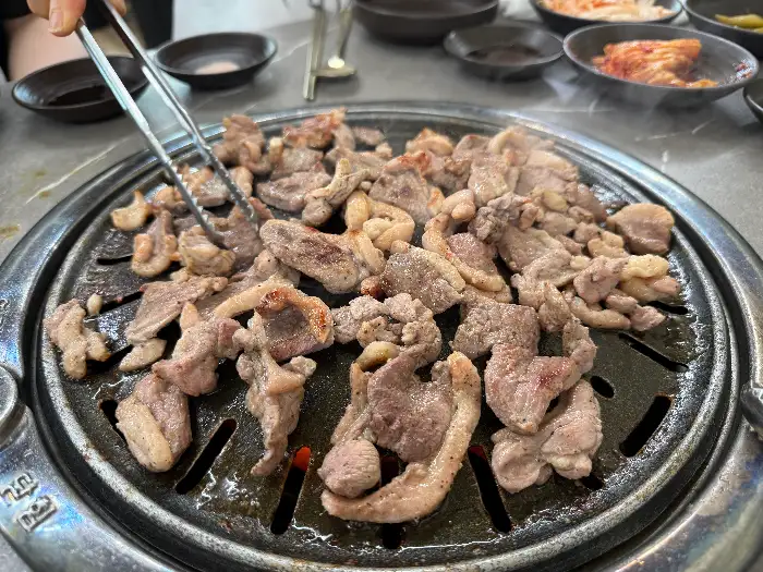 잘 익은 오리 주물럭을 집게로 집어 올리는 모습