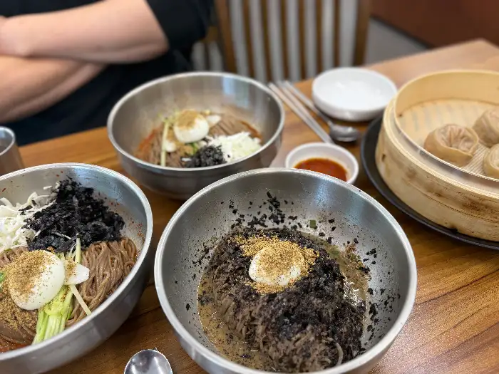 테이블에 놓인 여러 음식들, 막국수와 만두가 보인다.