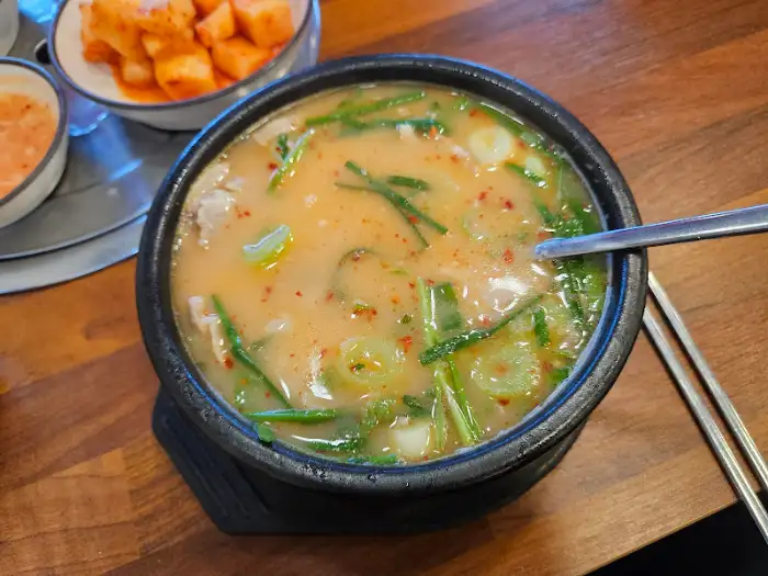 따뜻한 국물과 수육이 담긴 검은색 뚝배기
