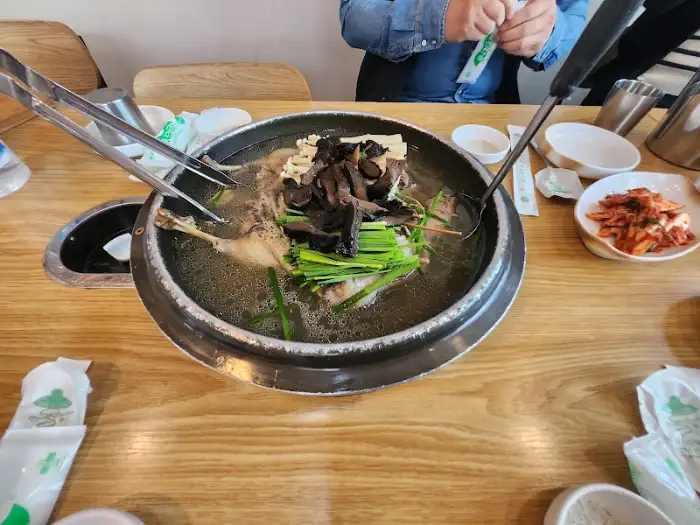 식탁 위에 차려진 음식들과 끓고 있는 오리탕