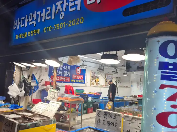 간판에 '바다먹거리장터'라고 적힌 가게의 전경, 파란색과 빨간색으로 된 간판이 눈에 띈다.
