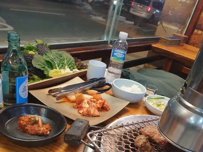 테이블에 놓인 돼지갈비와 쌈 채소, 소주병.