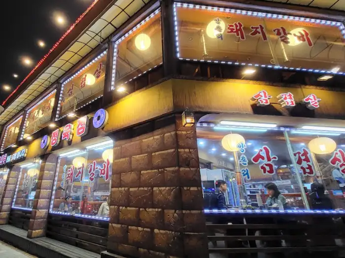 밤에 본 식당 외부 모습, 여러 간판이 조명으로 빛나고 있다.