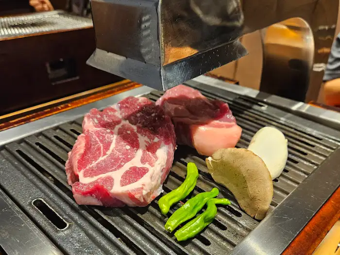 불판 위에서 익어가는 두툼한 삼겹살 덩어리