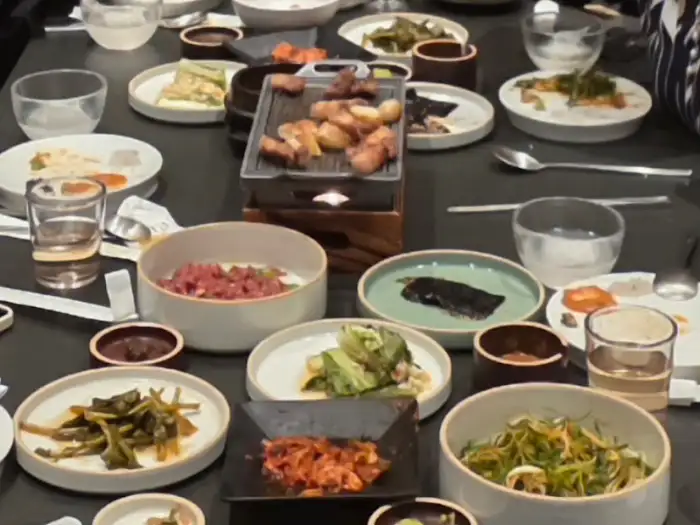 테이블 위에 다양한 반찬과 고기, 밥 등이 차려져 있다.