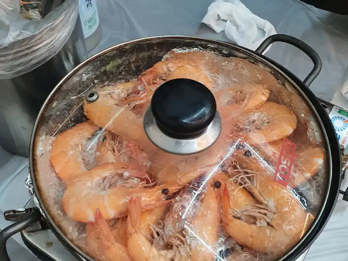 투명한 뚜껑 아래 김이 모락모락 나는 새우 요리
