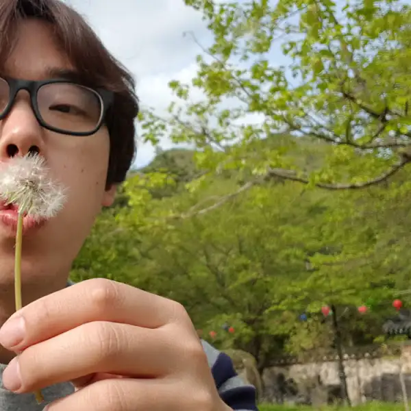 사람이 민들레 씨앗을 불고 있는 모습
