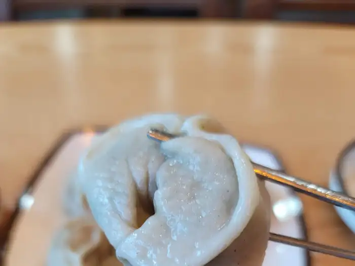 메밀 만두 하나를 젓가락으로 집은 모습