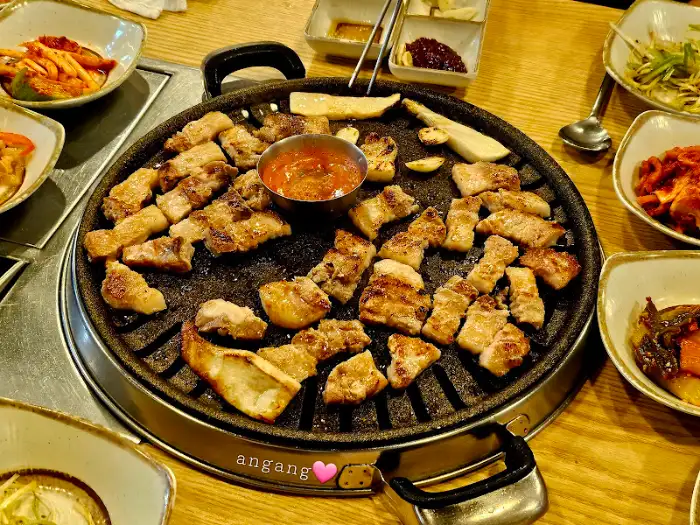 노릇하게 익은 삼겹살 조각들이 돌판 위에 올려져 있습니다.
