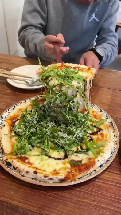 루꼴라 피자 위에 치즈가 늘어나는 모습