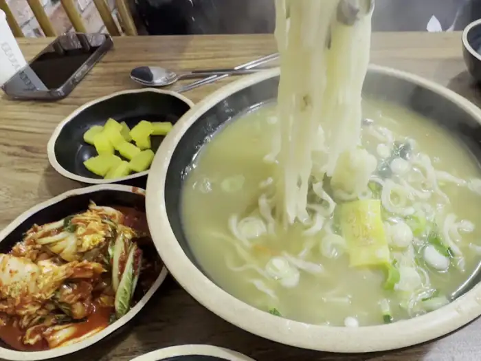 들고 있는 젓가락으로 칼국수 면을 건져 올리는 모습