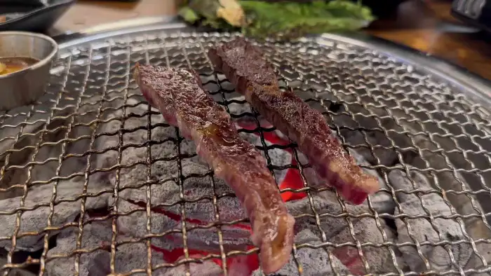 숯불 위에서 익어가는 두툼한 한우 꼬치