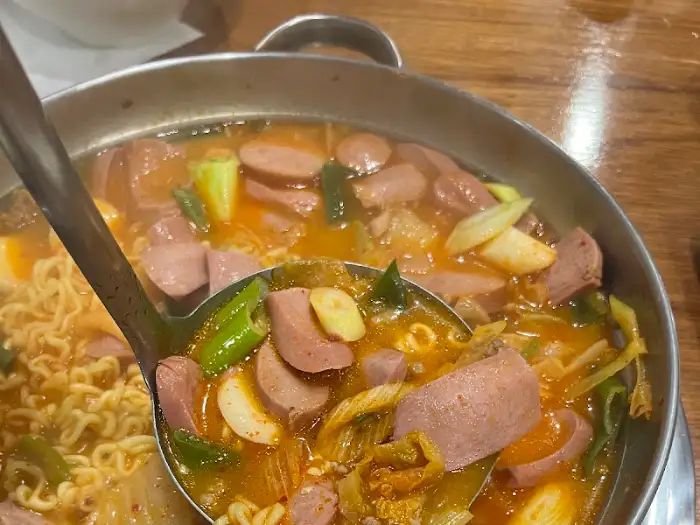 부대찌개 국자를 이용하여 햄과 국물을 뜨는 모습