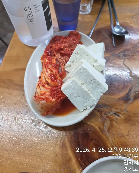접시에 담긴 김치와 하얀 두부 조각들이 보인다.