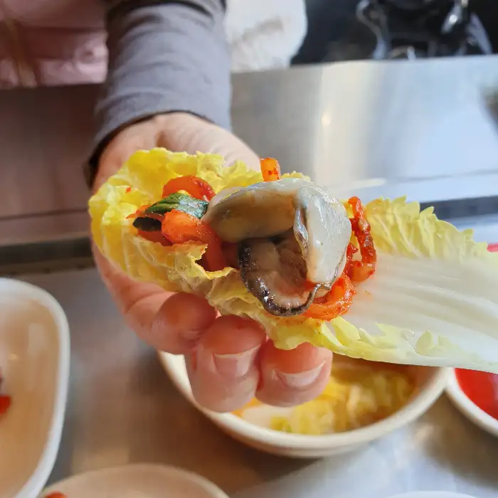 배추에 굴과 보쌈을 싸서 먹는 모습
