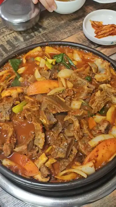 푸짐하게 담긴 갈비찜의 모습. 큼직한 갈비 조각과 채소, 양념이 어우러져 있습니다.