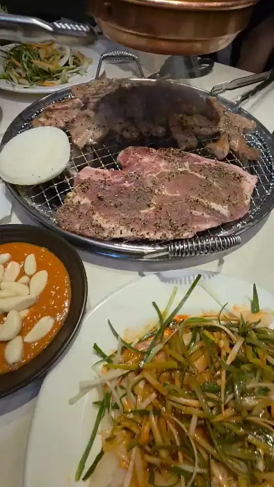 불판 위에서 익고 있는 고기와 곁들임 반찬