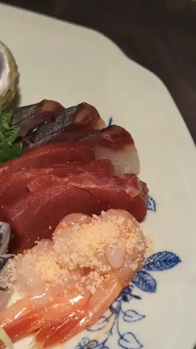 잔잔한 조명 아래 정갈하게 담긴 사시미 한 점
