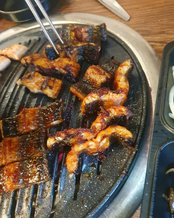 숯불 위에서 익어가는 다양한 장어 조각들