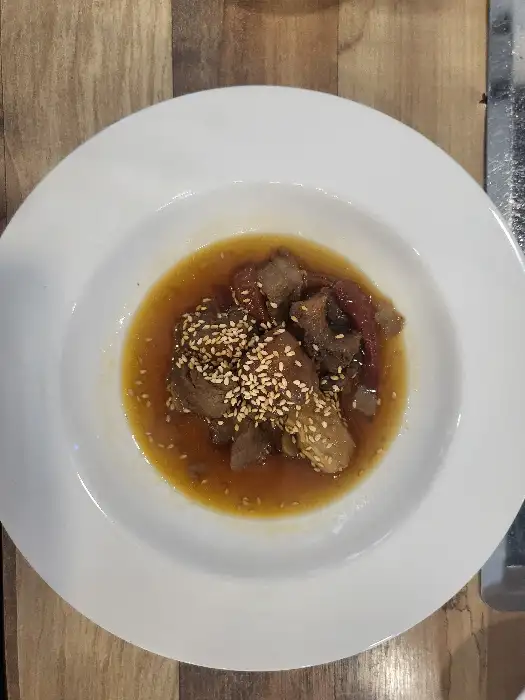 한우 조각과 함께 소스가 담긴 흰 접시