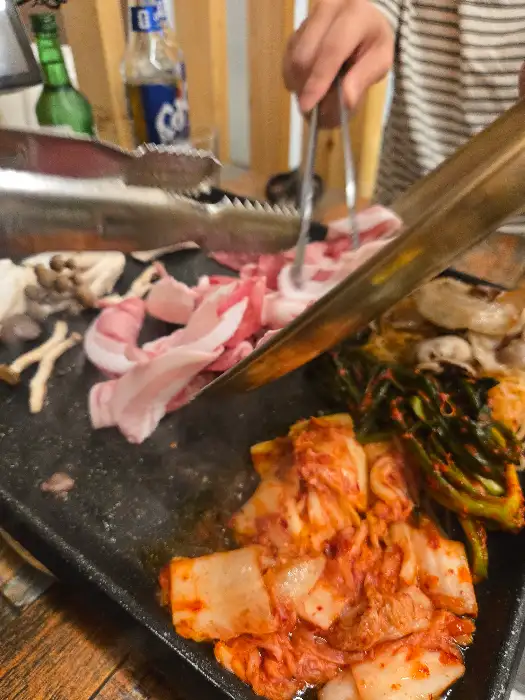잘게 썰린 대패삼겹살과 김치가 불판 위에서 익어가고 있는 모습
