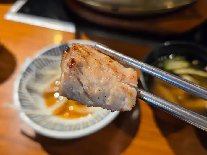 집게로 집어 올린 잘 익은 돼지갈비 한 점
