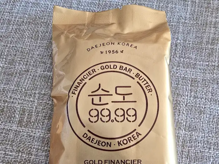 순도 99.99 골드 휘낭시에가 담긴 황금색 포장 봉투